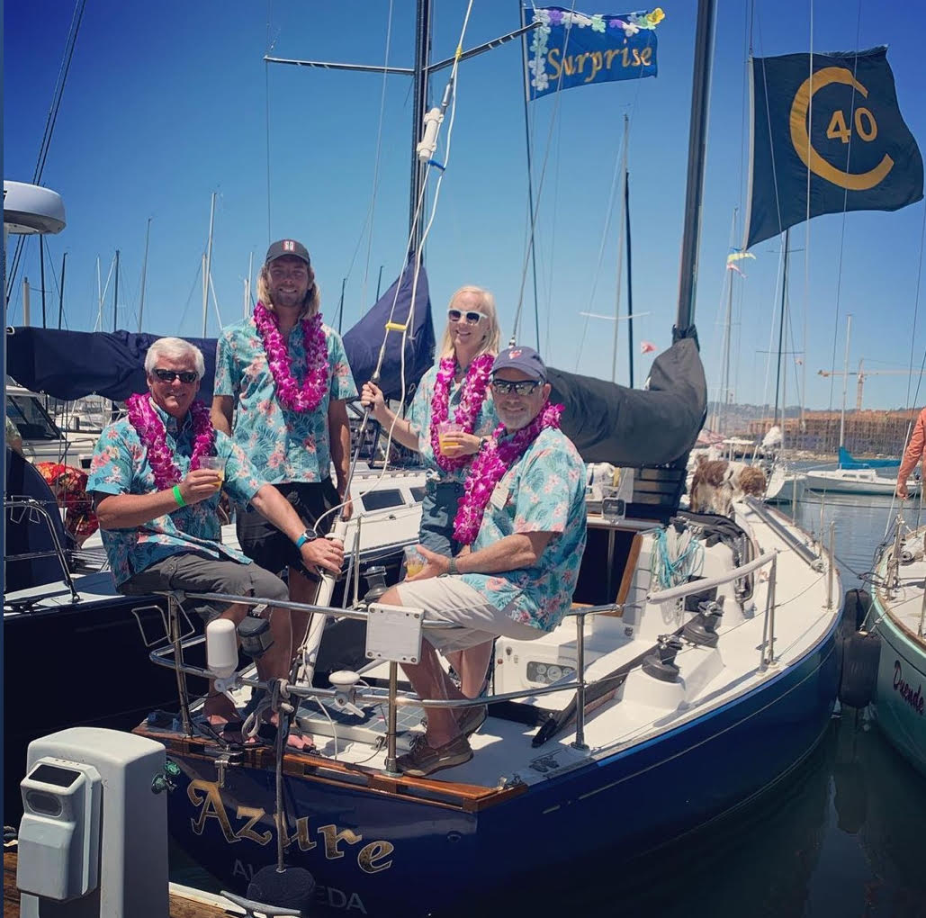 Four people wearing leis and matching Hawaiian shirts on sail boat Azure at dock
