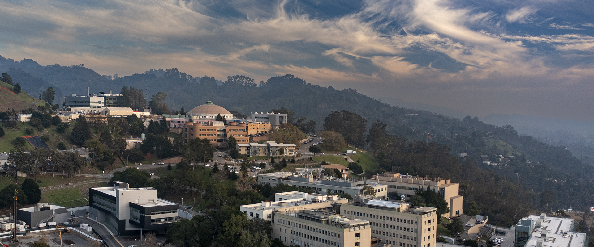 Aerial view of Berkeley Lab with hills, haze and clouds in the background